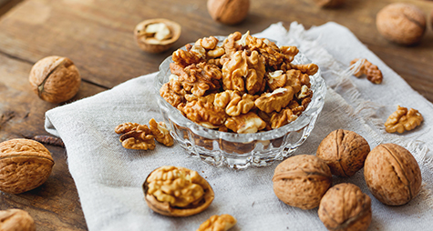 Glass bowl with walnuts on rustic homespun napkin. Healthy snack.
