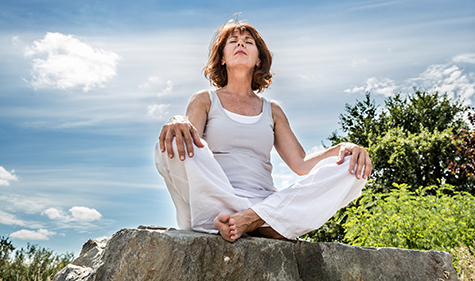 50s yoga woman seeking for spiritual balance over blue sky