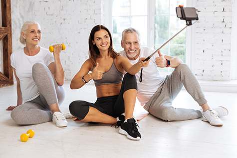 Positive delighted fitness coach holding monopod with telephone
