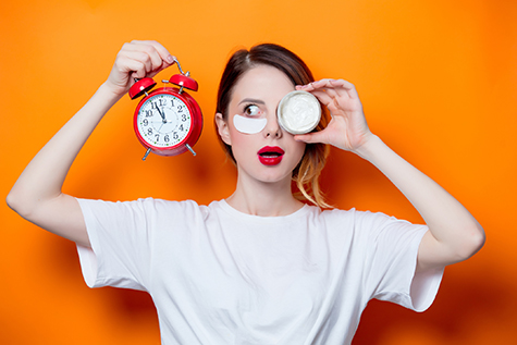 Woman using eye patch for her eyes and care lips on orange background