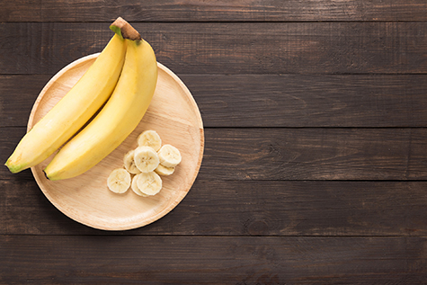 Bananas in a wooden dish on a wooden background.