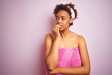 African american woman wearing shower towel after bath over pink isolated background looking stressed and nervous with hands on mouth biting nails. Anxiety problem.