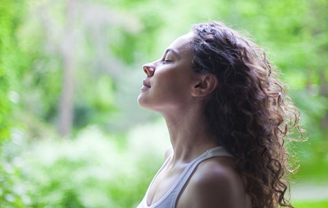Woman breathing fresh air outdoors in summer