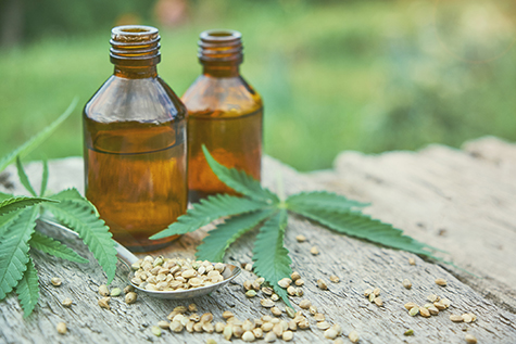 hemp leaves on wooden background, seeds, cannabis oil extracts in jars