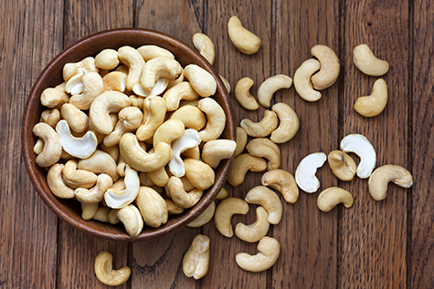 Bowl of halved cashew nuts in a wooden bowl