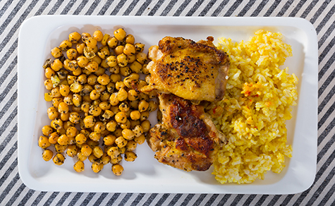 Grilled chicken thighs with garbanzo and yellow rice at plate