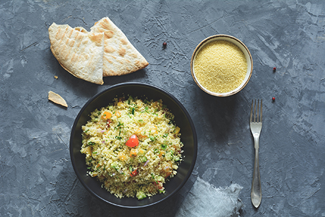 Tabbouleh with cous cous and arabic flatbread on concrete background