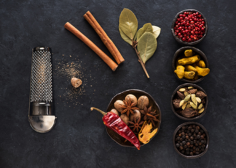 Indian spices and herbs in bowls on a black concrete background, top view, flat lay