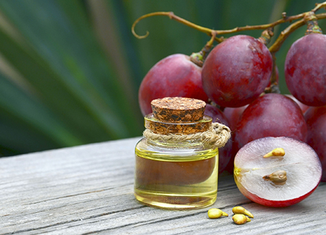 Grape seed oil in a glass jar and fresh grapes on old wooden table in the garden.Spa,Bio,Eco products concept.