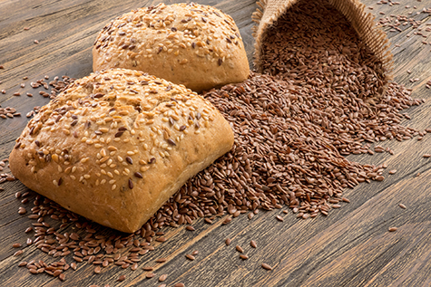 Flax seeds in linen and Bread with flax seeds and sesame on a dark wooden table