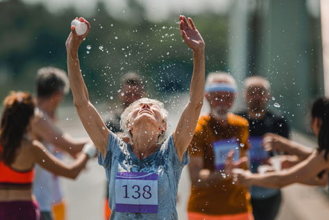 Senior marathon runner refreshing herself with water during a race.