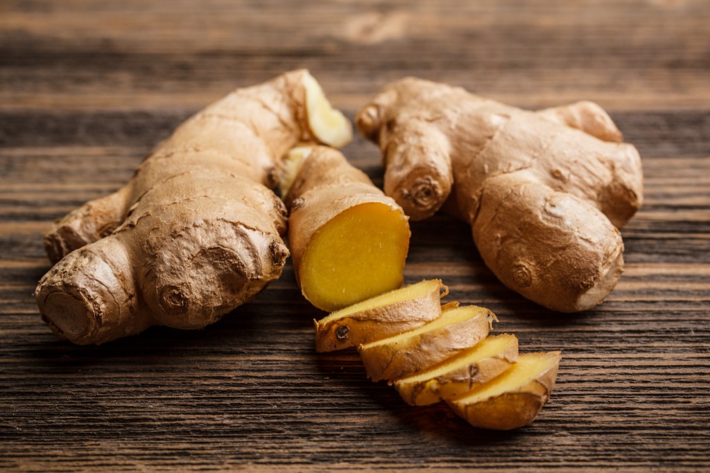 Fresh ginger whole and chopped on rustic wood surface