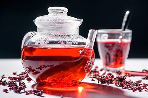 glass teapot with hibiscus tea and cup with spoon on table