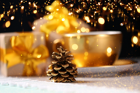 Gold pine cone on blurred golden gift boxes and coffee cup background