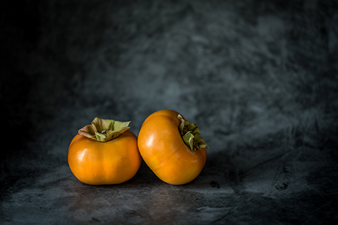 Two persimmons on a black background