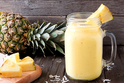 Pineapple smoothie in a mason jar, scene against wood