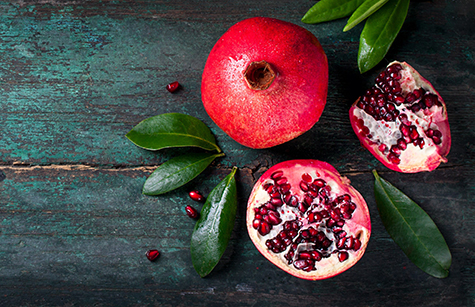 Fresh juicy pomegranate - whole and cut, with leaves