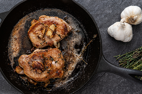 Photograph of pork chops being cooked in a cast iron skillet