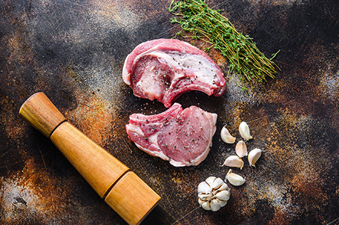 set organic pork chop steaks over dark background wood and rustic steel, close up top view vertical