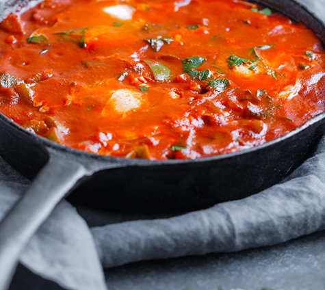Traditional recipe of popular Middle Eastern dish shakshuka with green bell peppers, tomatoes, onion, garlic and poached eggs.