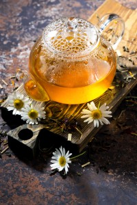 fragrant chamomile tea in a glass teapot on dark background
