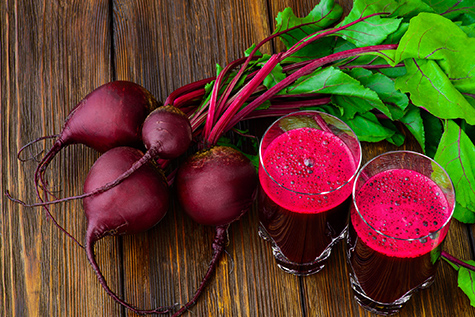 Glass of fresh beetroot juice with bets on wooden table