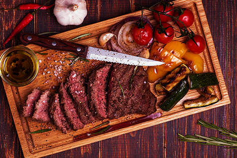 BBQ steak with grilled vegetables on cutting board