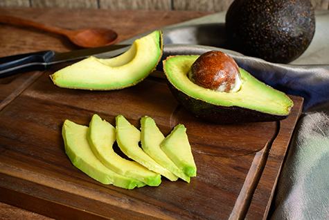 Ripe slice avocado on wooden cutting board