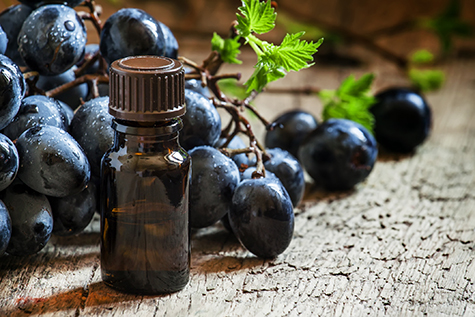 Grape seed oil in brown bottle, bunch of grapes, vine