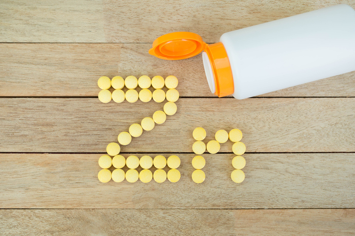 Yellow pills forming shape to Zn alphabet on wood background