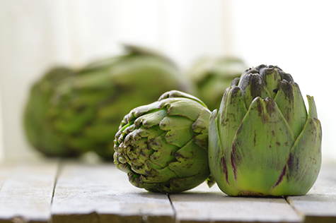 Some artichokes on a white wooden table
