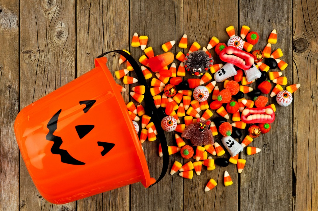Halloween Jack o Lantern pail with spilling candy over wood