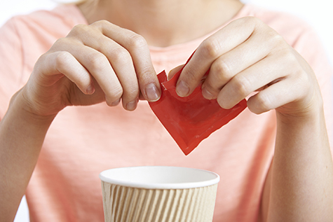 Woman Adding Artificial Sweetener To Coffee