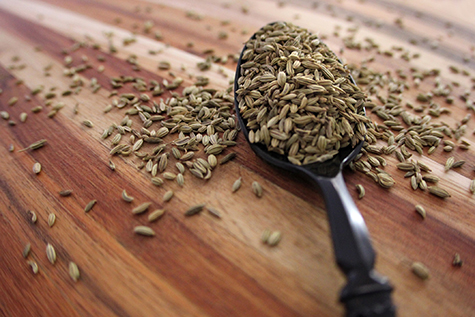 Spoonful of fennel seeds on wooden board