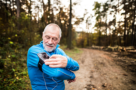 Senior runner in nature with smart phone and earphones.