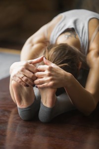Close up of woman in paschimottanasana pose, home interior backg