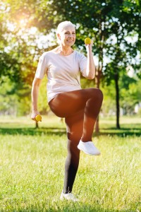 Overjoyed retired woman doing step exercises with dumbbells