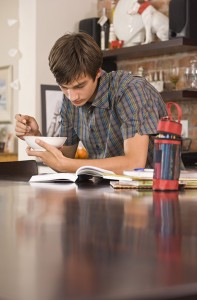 Teenage boy doing homework at kitchen table