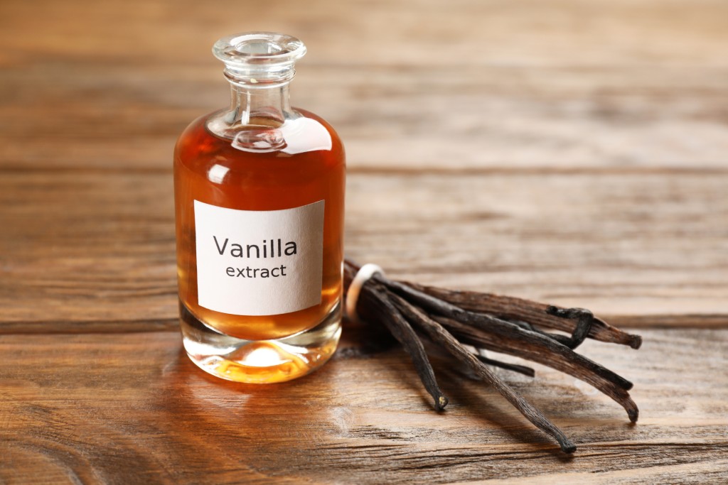 Aromatic vanilla extract and beans on wooden table